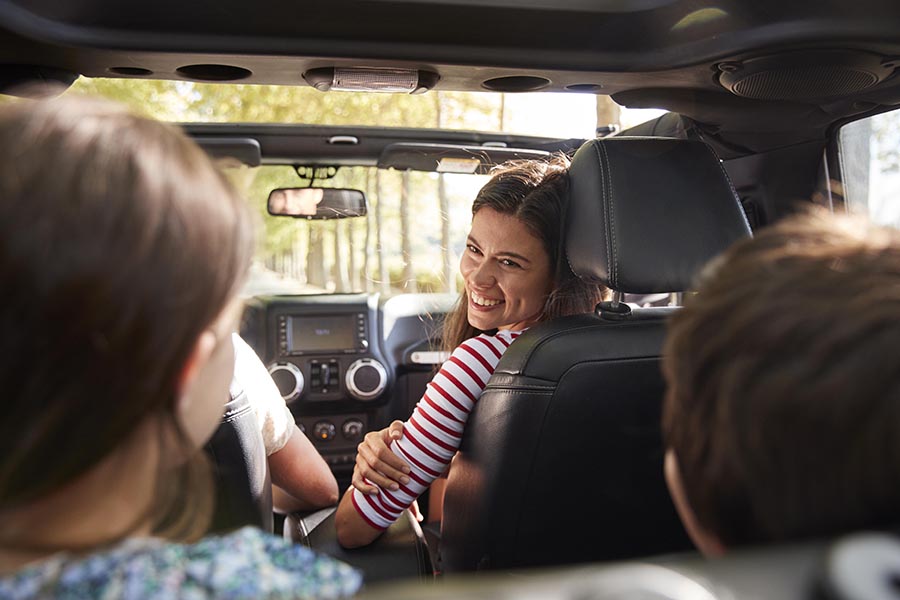Blog - Mother in Passenger Seat of a Black SUV Looks Happily at Her Children in the Back Seat